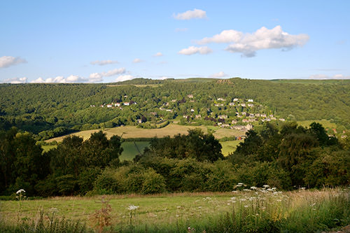 aerial-grindleford Green hills and fields with scattered houses under a blue sky with a few clouds.